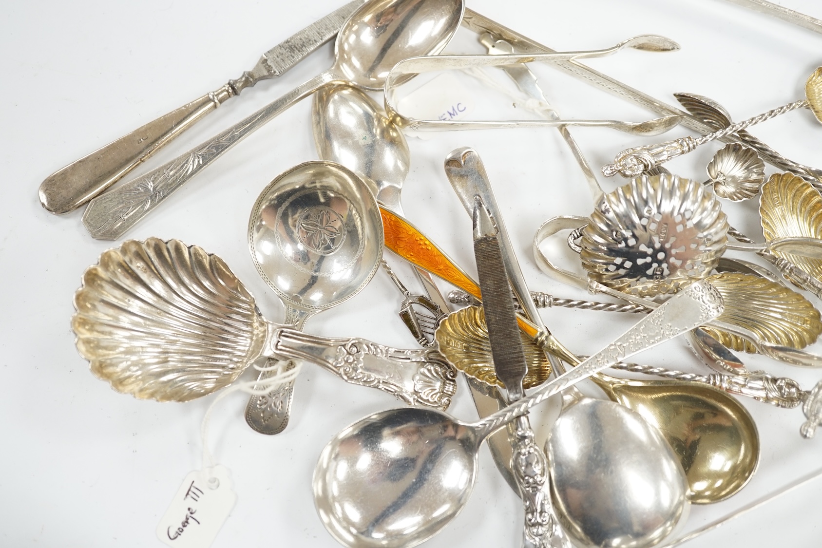 A collection of assorted small silver, sterling and white metal flatware, including two 19th century caddy spoons, enamelled spoon, sifter spoon, teaspoons, sugar tongs, etc. 9oz and two nail implements. Condition - poor